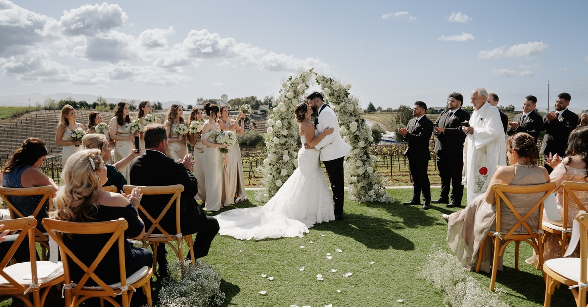 Outdoor ceremony at a vineyard wedding venue in California with floral arch and scenic vineyard views