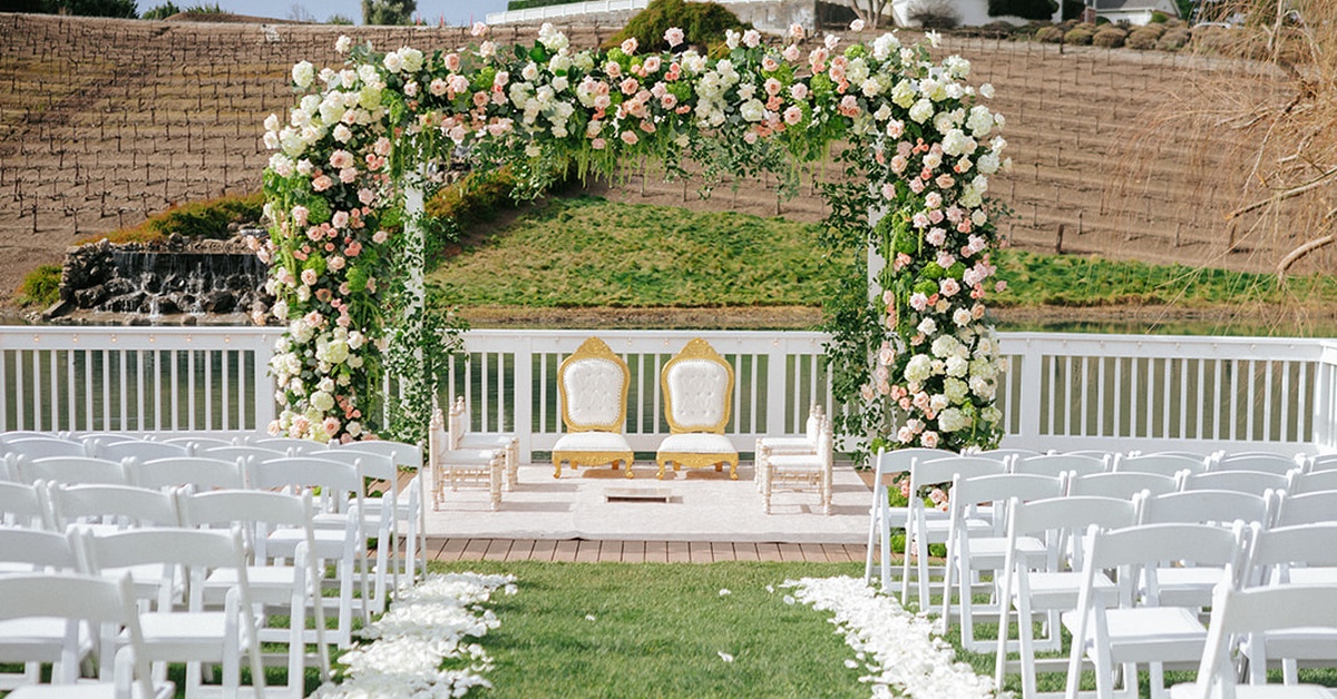Outdoor vineyard wedding ceremony setup with floral arch and white chairs at a luxury wedding venue near Morgan Hill
