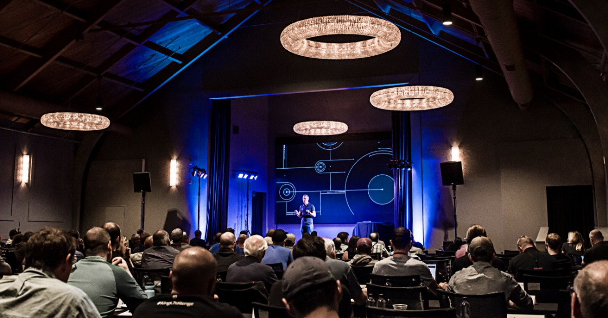 Speaker presenting on stage at a corporate event venue in California with audience engagement