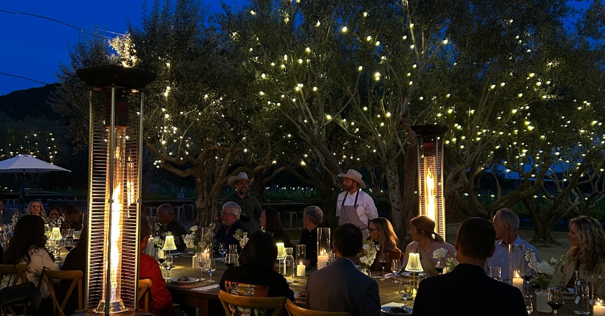 Outdoor evening business gala at a California vineyard private event venue with ambient lighting and seated guests