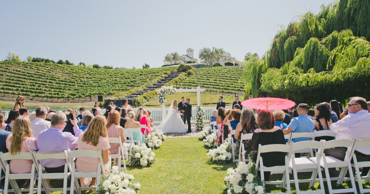 Outdoor vineyard wedding ceremony at Léal Vineyards in Hollister CA with guests overlooking rolling vines