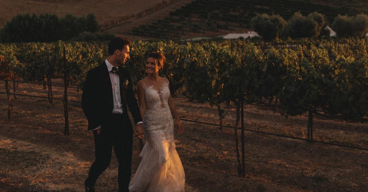 Couple walking through vineyard at sunset enjoying all inclusive wedding services at a scenic venue