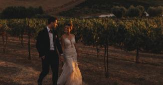 Couple walking through vineyard at sunset enjoying all inclusive wedding services at a scenic venue